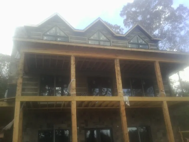 Dormers and porch framing on a large log home under construction — Roof Coating work by our crew in Fenton